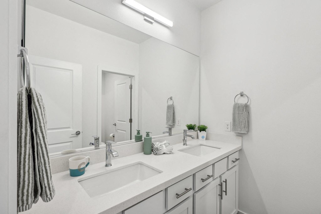 A bathroom with a white sink and a striped towel hanging on the door.