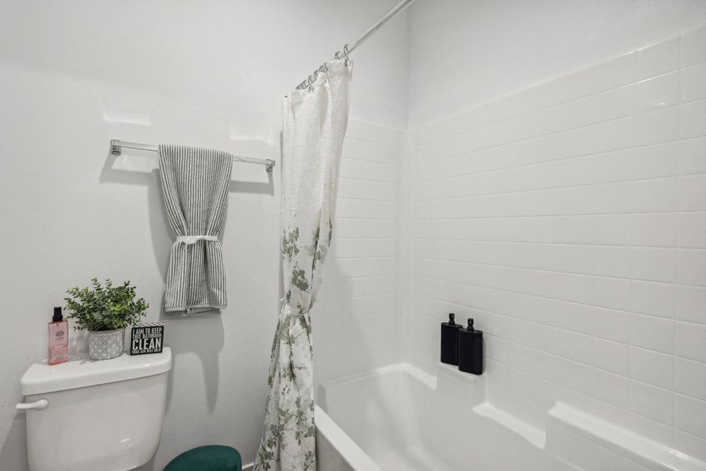 A white bathroom with a white toilet and a white bathtub.