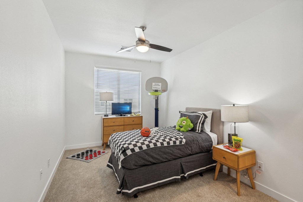 A bedroom with a bed, a ceiling fan, and a window with blinds.