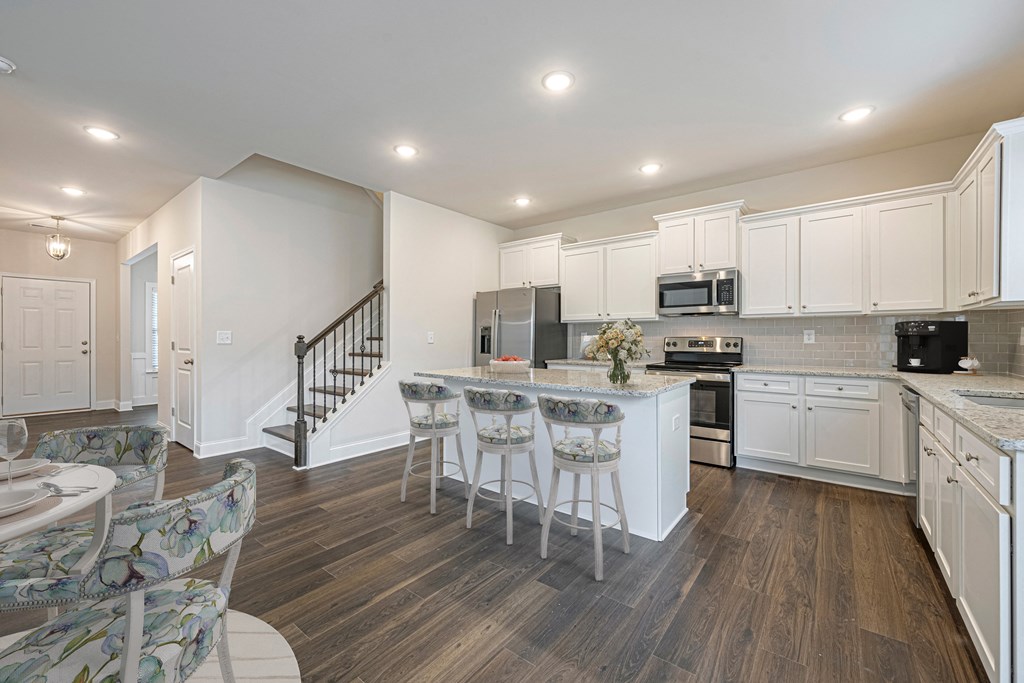a kitchen with white cabinets and a island with bar stools