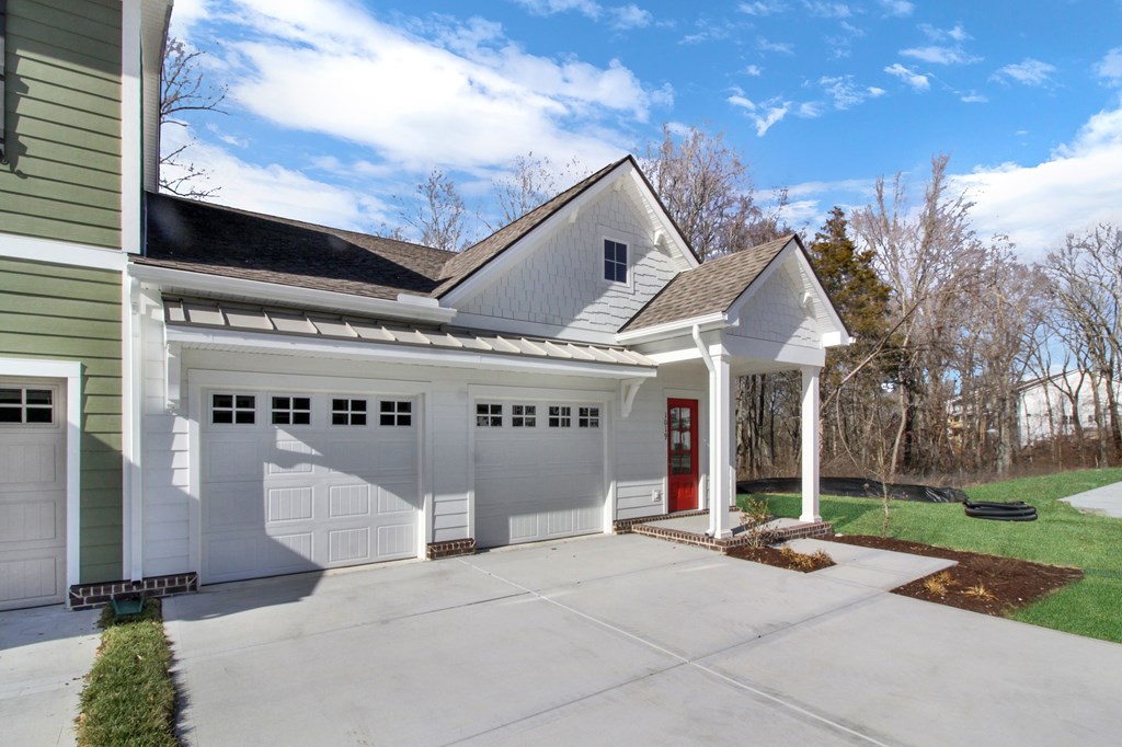 A white house with a red door and a green garage door.