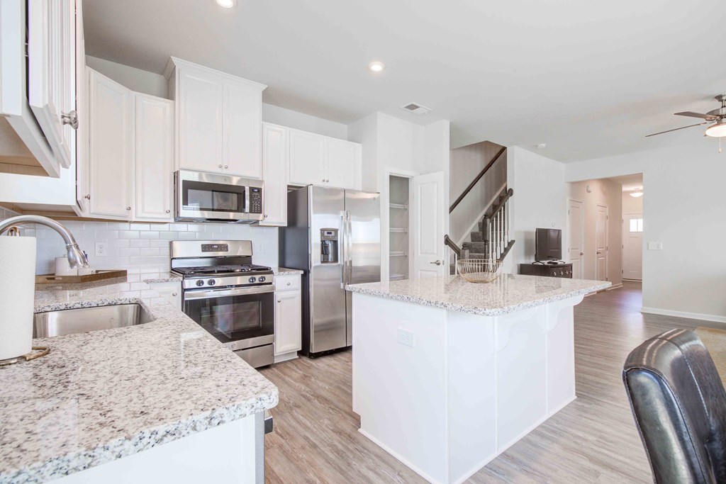 Sleek, expertly designed kitchen with granite countertops, center island, and premium stainless steel appliances