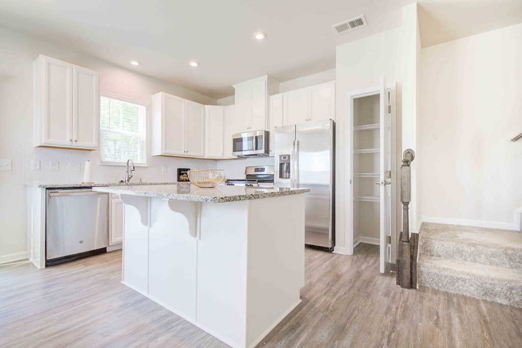 Modern white kitchen featuring premium stainless appliances and beautiful hardwood flooring throughout