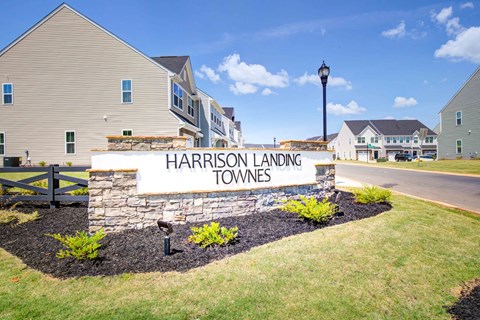 Welcoming community entrance featuring custom stone signage and manicured landscaping beds