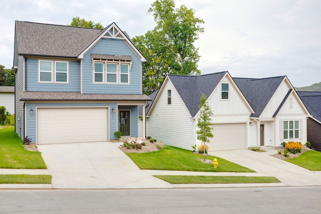 A blue house with a grey roof and white garage doors.
