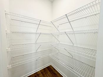 the spacious walk in closet in the second bedroom of the home has white wire shelves