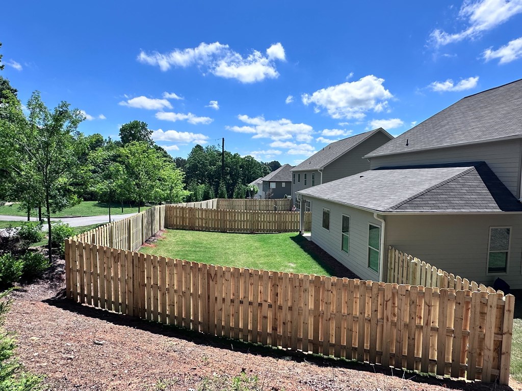 a wooden fence around a yard in front of a house