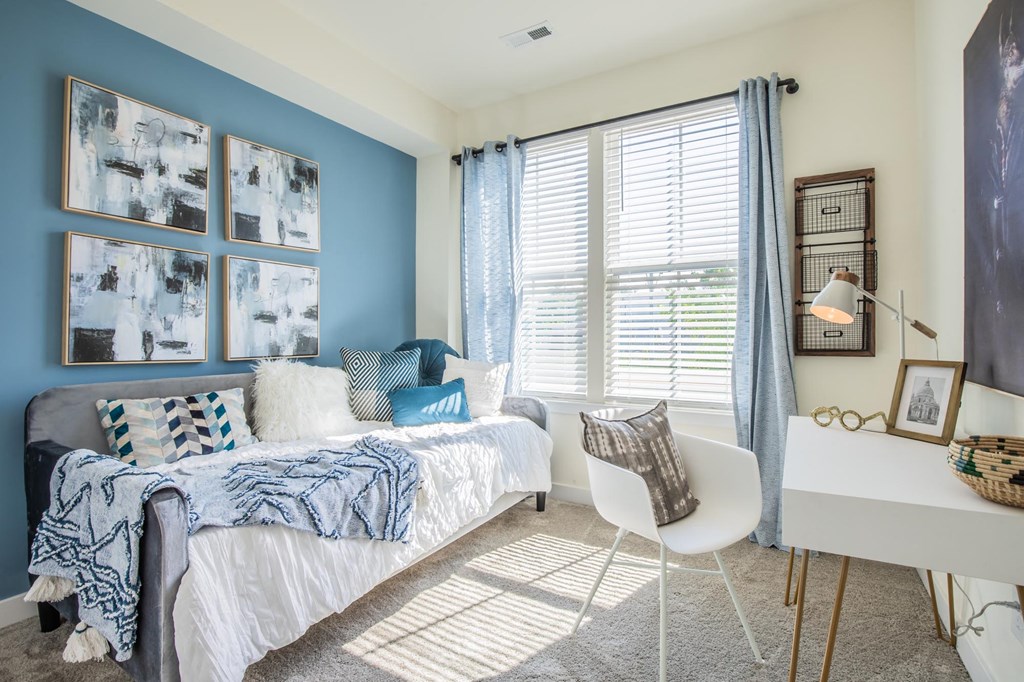 a bedroom with a bed and a desk and a window