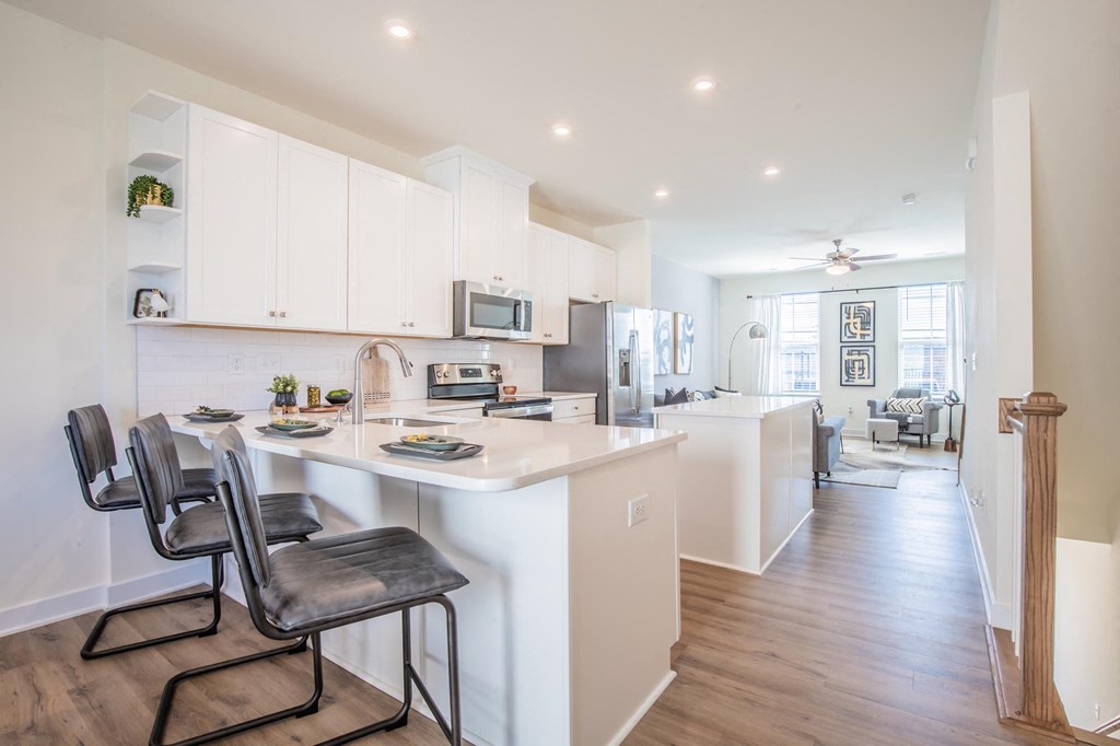 an open kitchen and dining area with white cabinets and a white counter top
