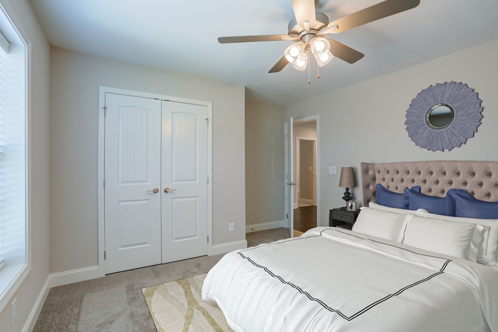 A bedroom with a white bed and a ceiling fan.