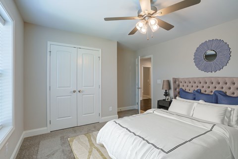 A bedroom with a white bed and a ceiling fan.