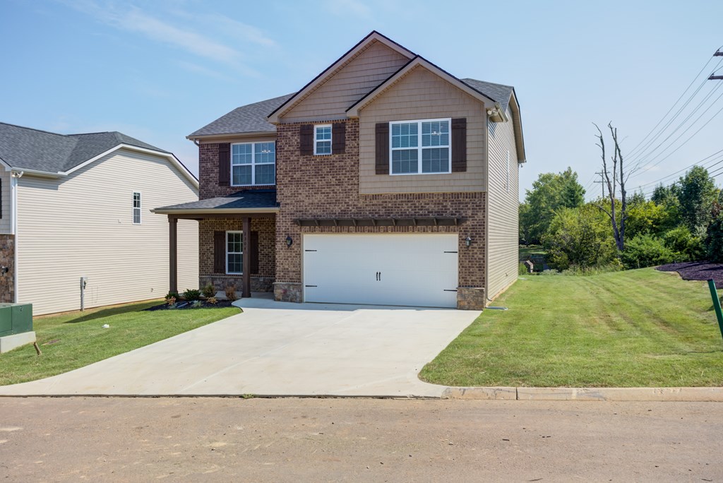 A two-story house with a garage is surrounded by a grassy area and a sidewalk.