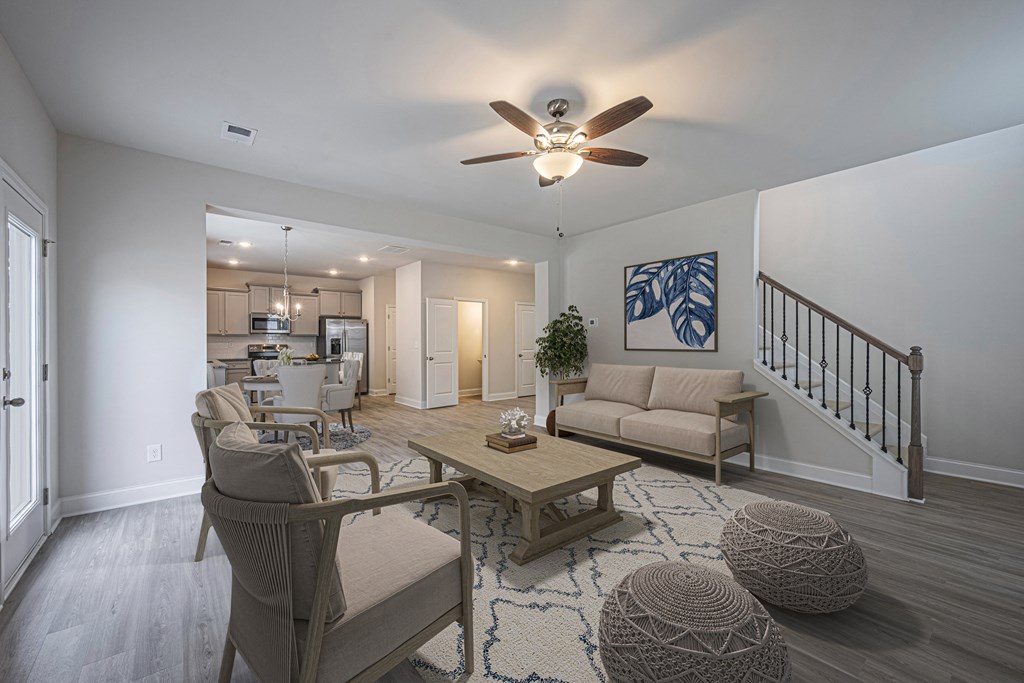 a living room with a ceiling fan and a staircase