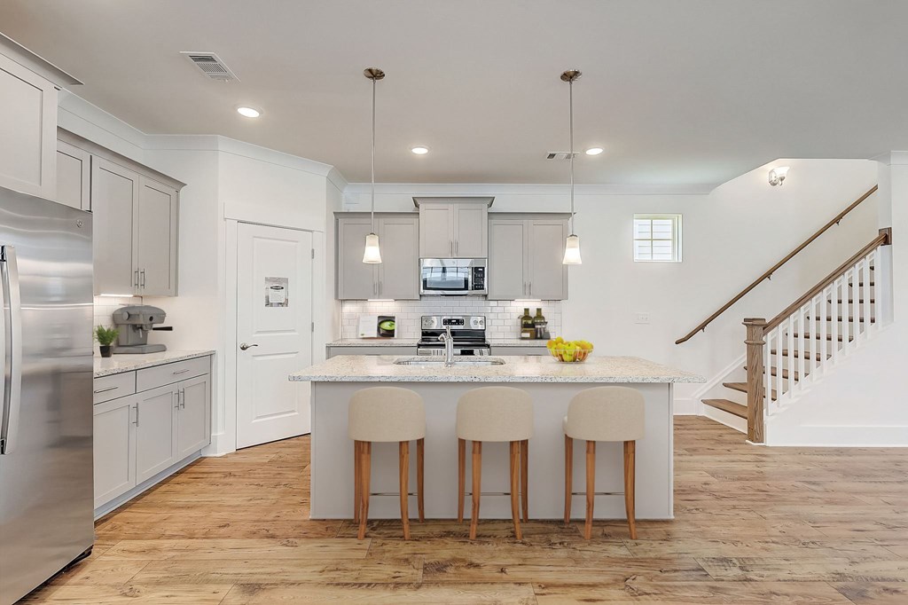 A kitchen with a white island and bar stools.