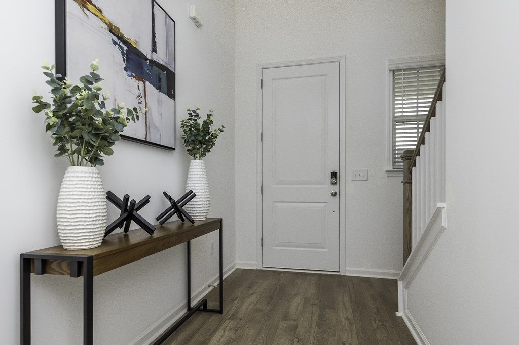 the entrance to a home with a white door and a hallway with a vase