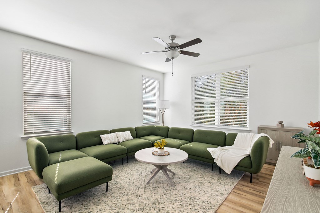 a living room with a green couch and a ceiling fan