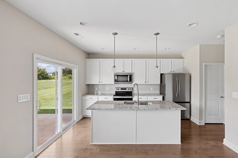 A kitchen with white cabinets and a marble countertop.