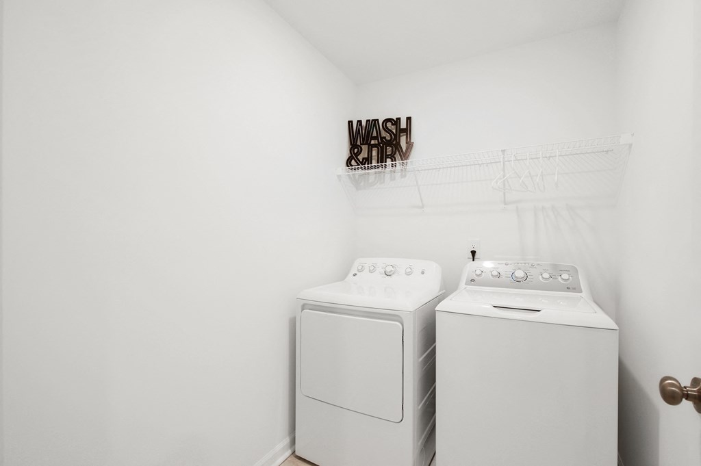 a white laundry room with two washes and a dryer
