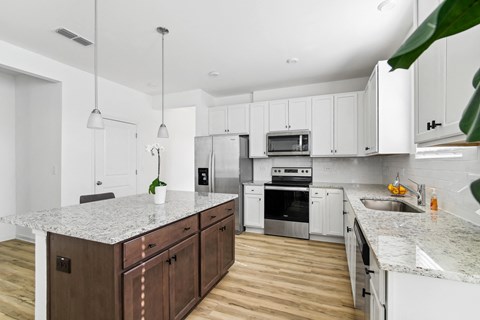 A kitchen with white cabinets and a wooden island.