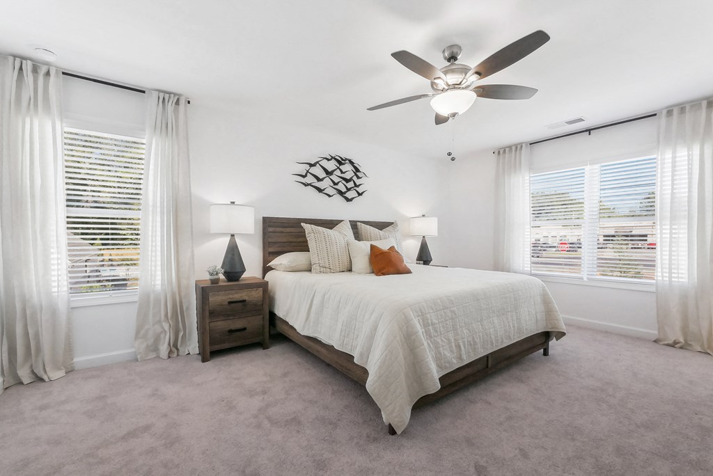 Primary bedroom with plush carpet and ample sunlight