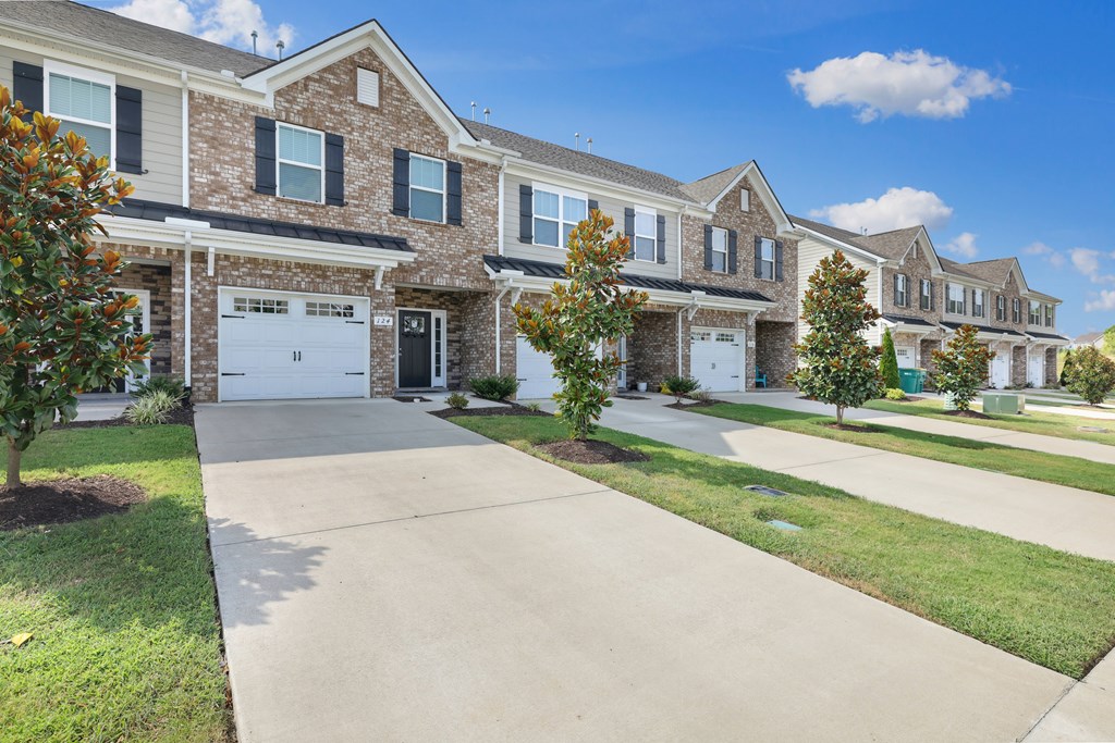 A row of houses with a driveway in the foreground.