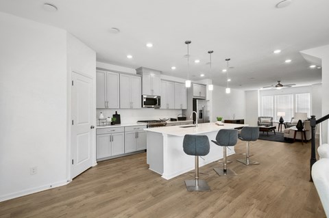an open kitchen and living room with white cabinets and a white counter top