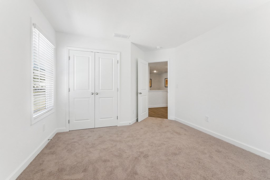 Bright bedroom with plush carpet and ample closet space