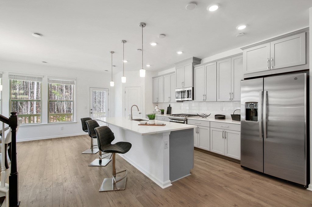 a white kitchen with a large island and stainless steel appliances