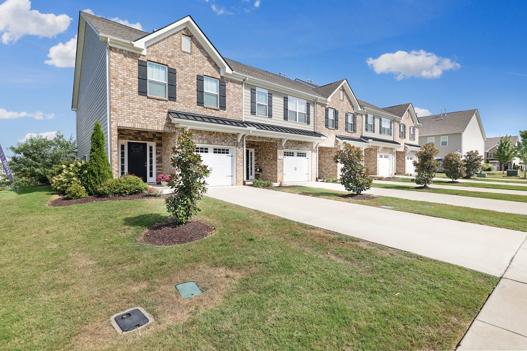 A row of houses with a green lawn in front.