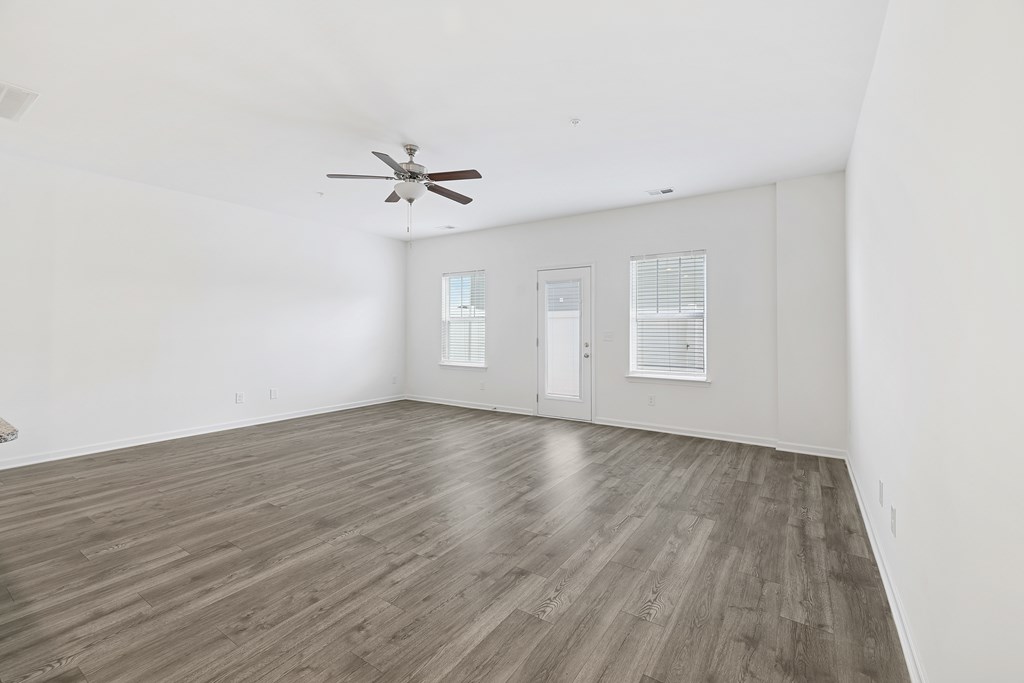 A room with a ceiling fan and wood flooring.