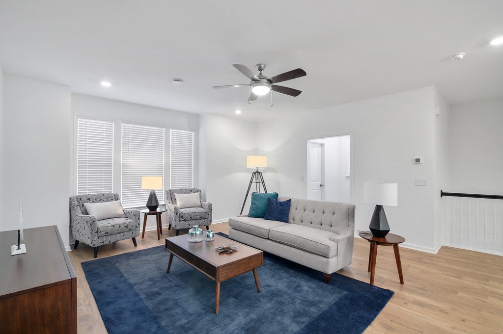 a living room with a couch and chairs and a ceiling fan