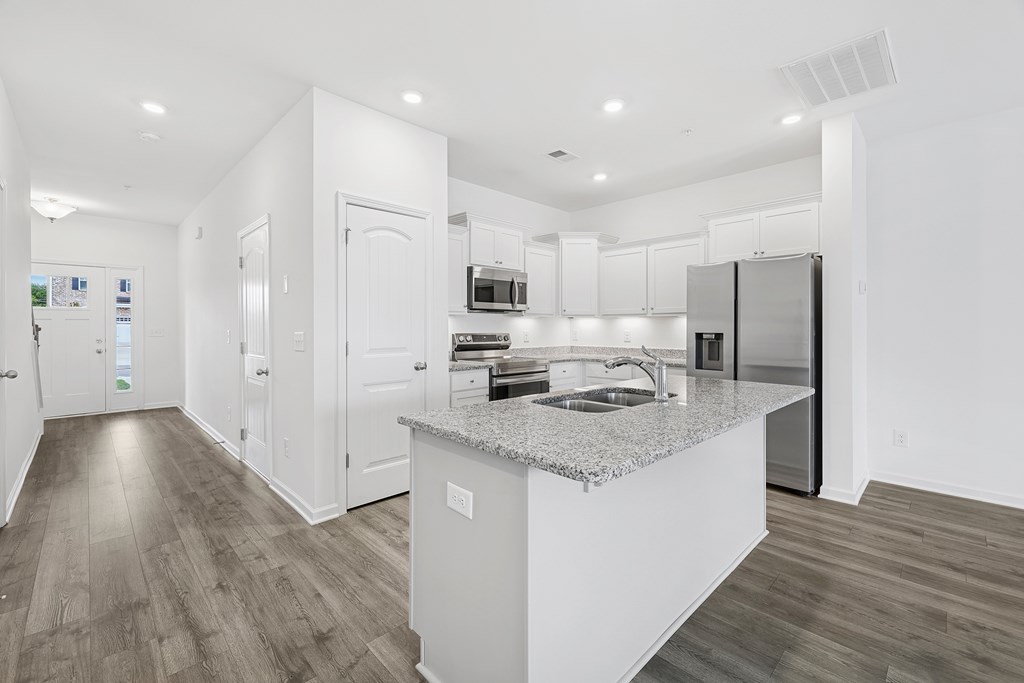 A modern kitchen with a granite countertop and stainless steel appliances.