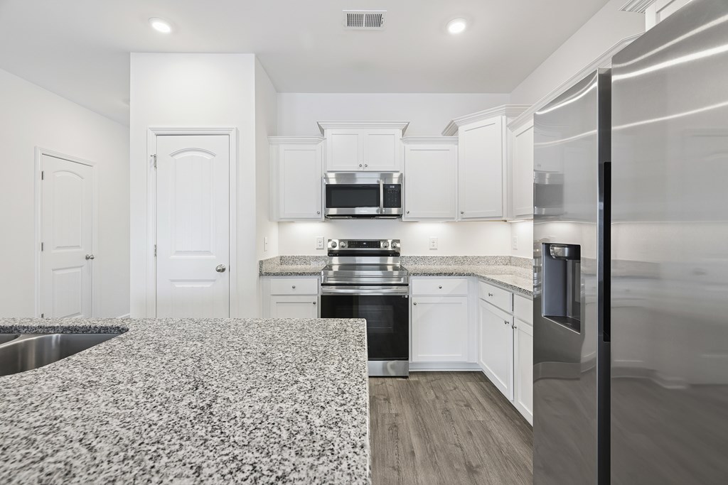 A kitchen with white cabinets and a patterned floor mat.