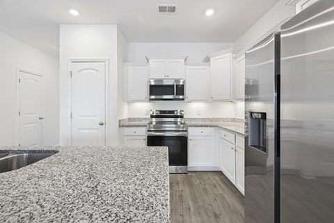 A kitchen with white cabinets and a patterned floor mat.