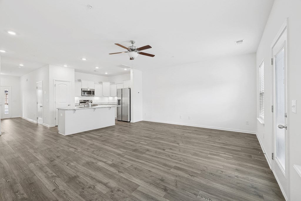 A spacious room with a ceiling fan and wooden flooring.