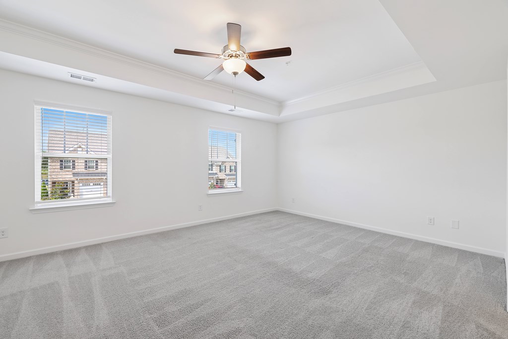 A room with a ceiling fan and two windows.