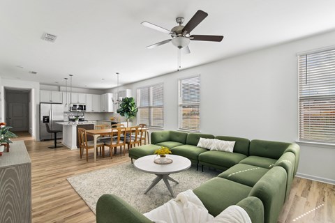 a living room with a green couch and a ceiling fan
