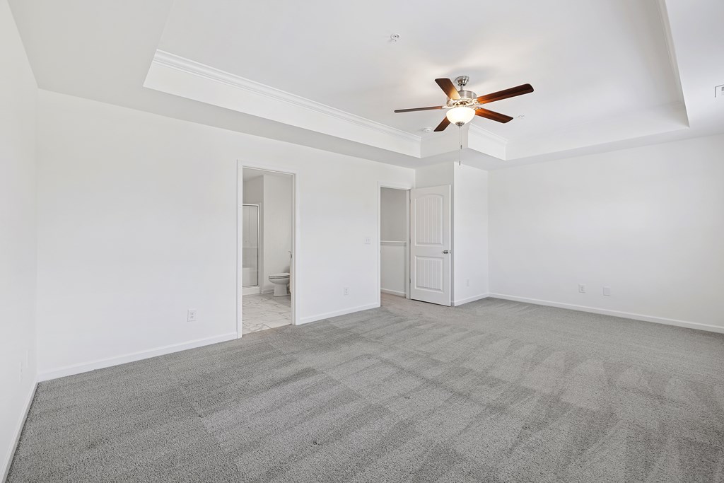 A room with a ceiling fan and carpeted floor.