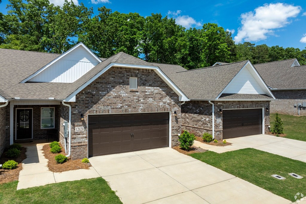 A house with a brown garage door and a stone wall.