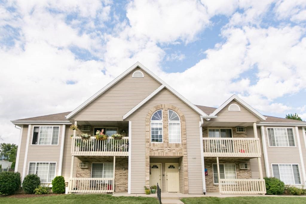 the front of a house with a yard and a cloudy sky