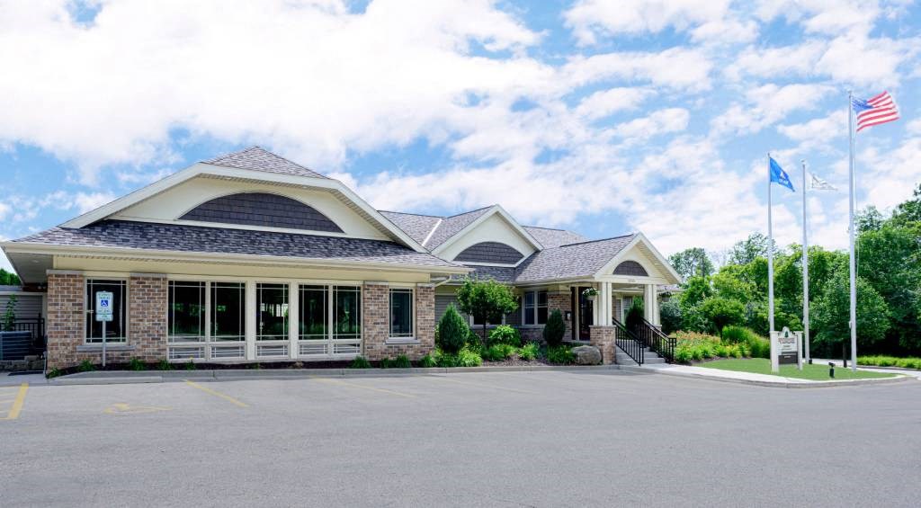the front of a building with two flags and a driveway