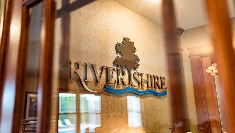the logo of the river shining company is shown on a glass door