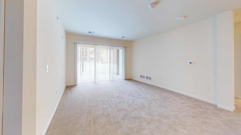 an empty living room with a door to a balcony