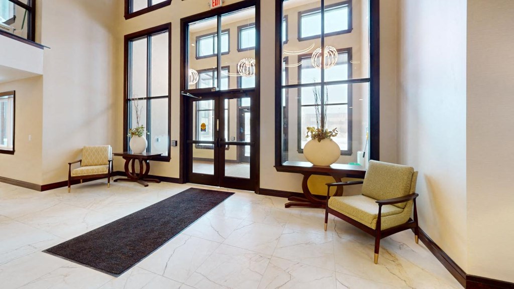 a lobby with large windows and chairs and a rug