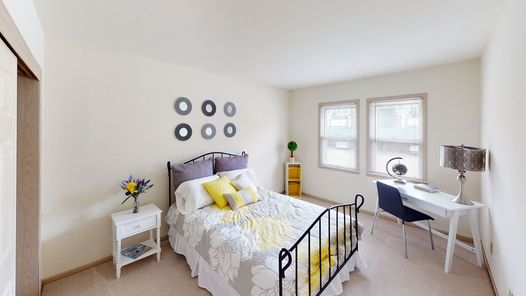 two windows in a bedroom with a bed and desk