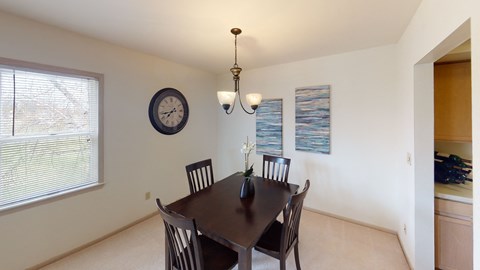 a dining room with a table and chairs and a clock on the wall
