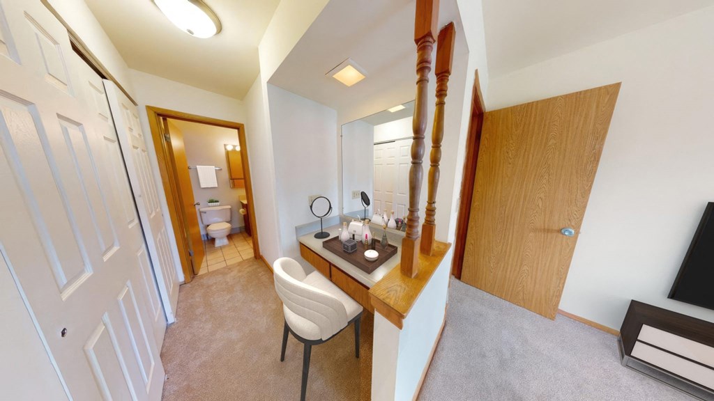 a bedroom with a desk and a bathroom with a toilet and a sink