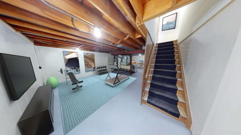 a home gym with a staircase and a tv