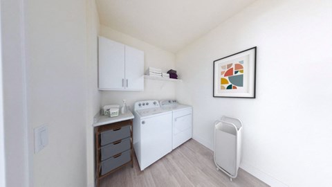 a small kitchen with white appliances and a painting on the wall