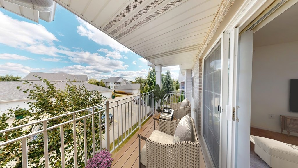 A balcony with a white railing and a wicker chair.